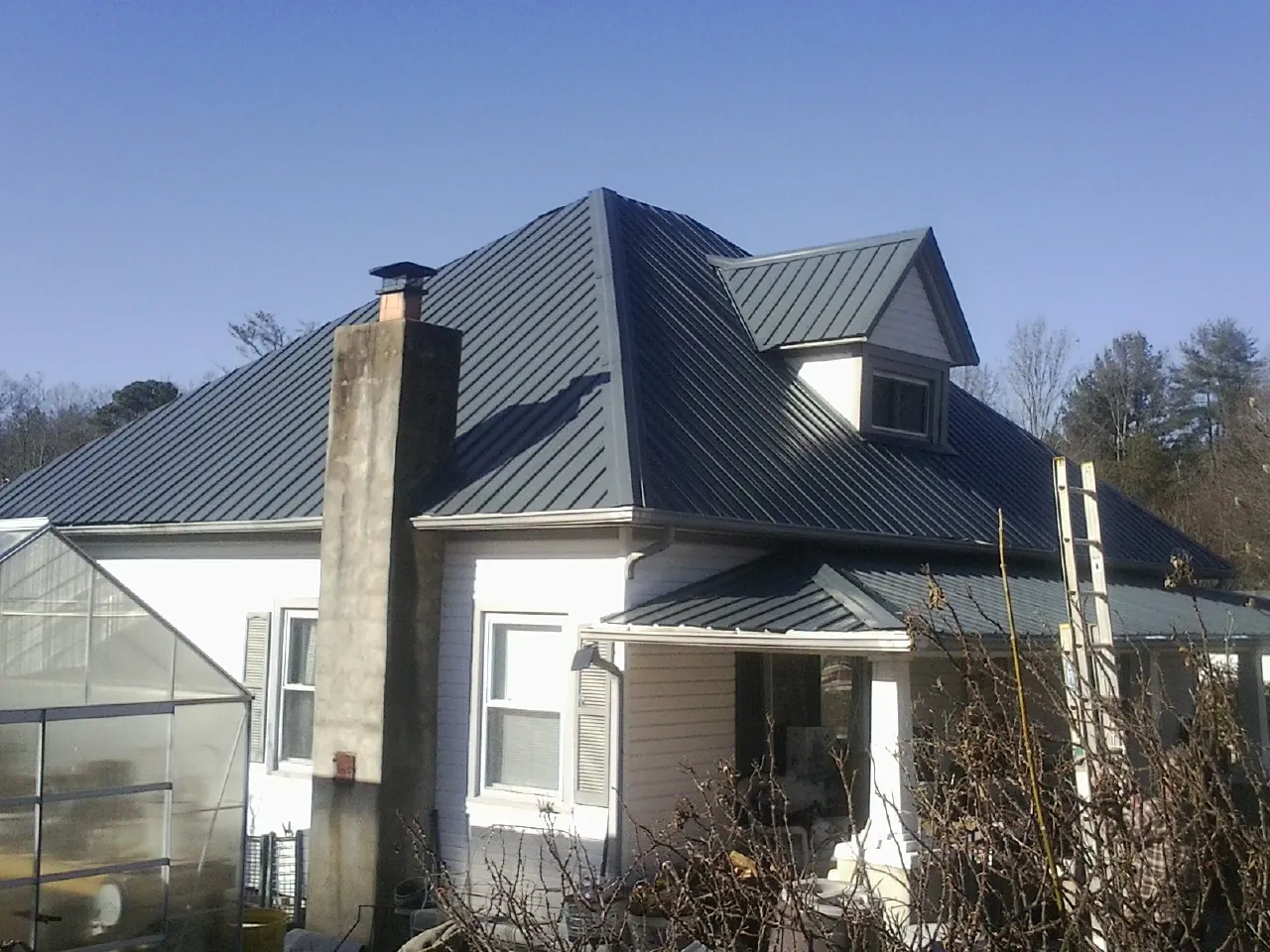 Dark blue standing seam metal roof on a white farmhouse with dormer — Slate & Tile Roof Repair by Roofing Brothers in Mountain City