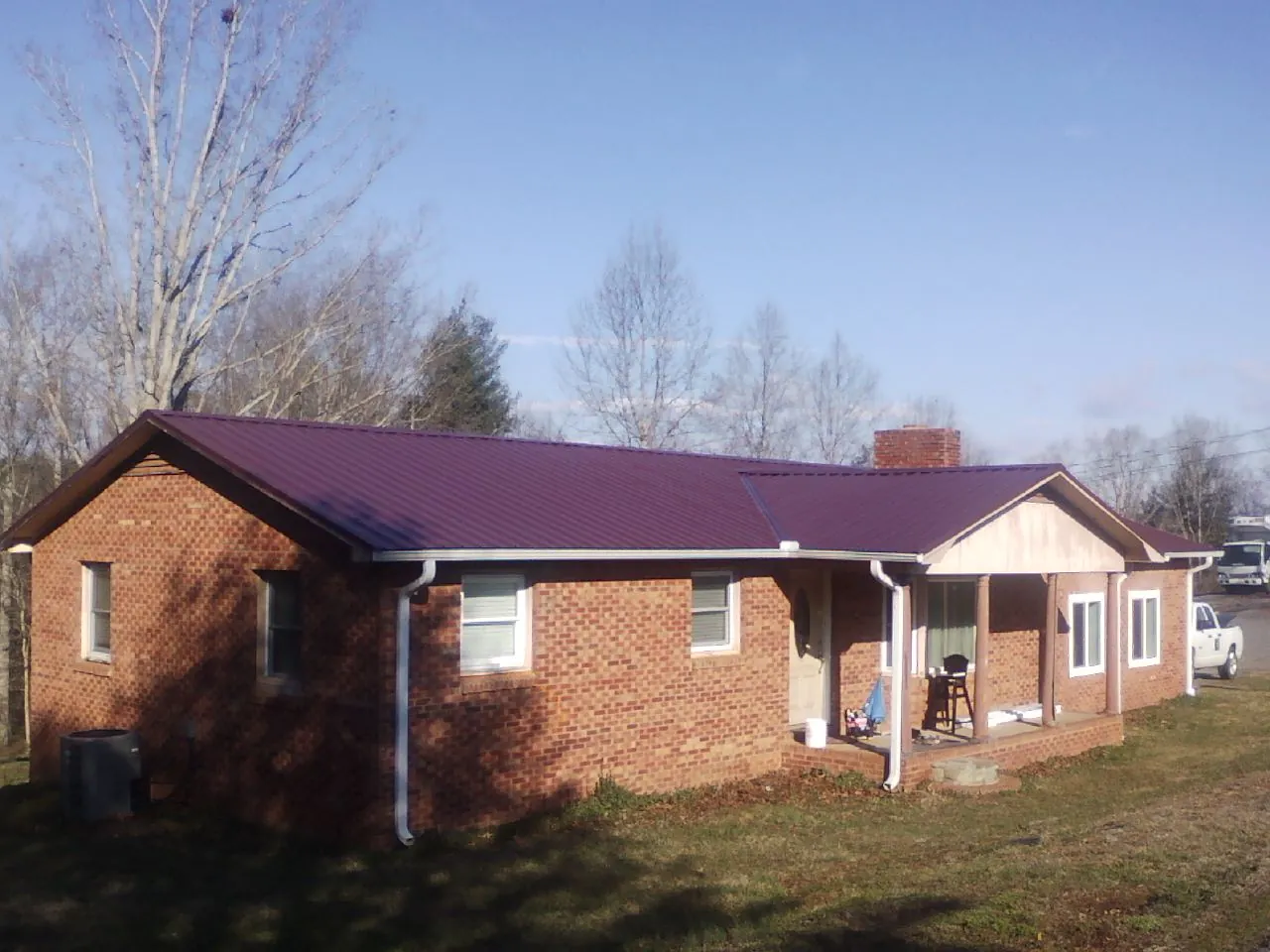 Burgundy metal roof on a brick ranch home with a new addition in Mountain City