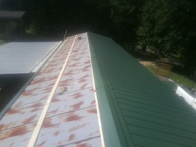 Old rusted panels beside newly installed green metal roofing — Wind Damage Roof Repair by Roofing Brothers in Mountain City