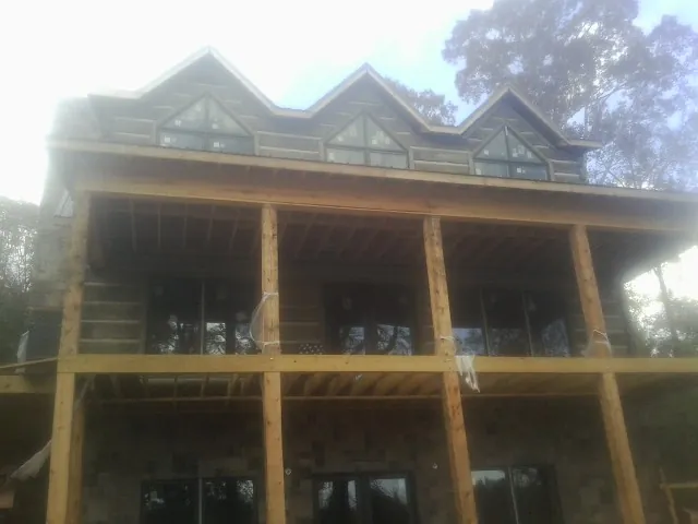 Dormers and porch framing on a large log home under construction — Roof Coating work by our crew in Mountain City