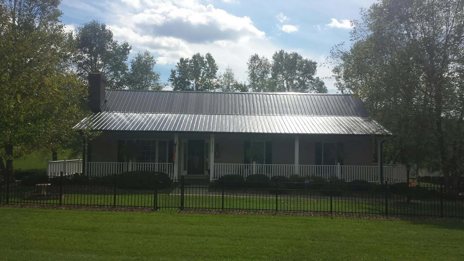 Gray metal roof on a brick ranch with a full width front porch — Gutter Guard Installation work by our crew in Mountain City