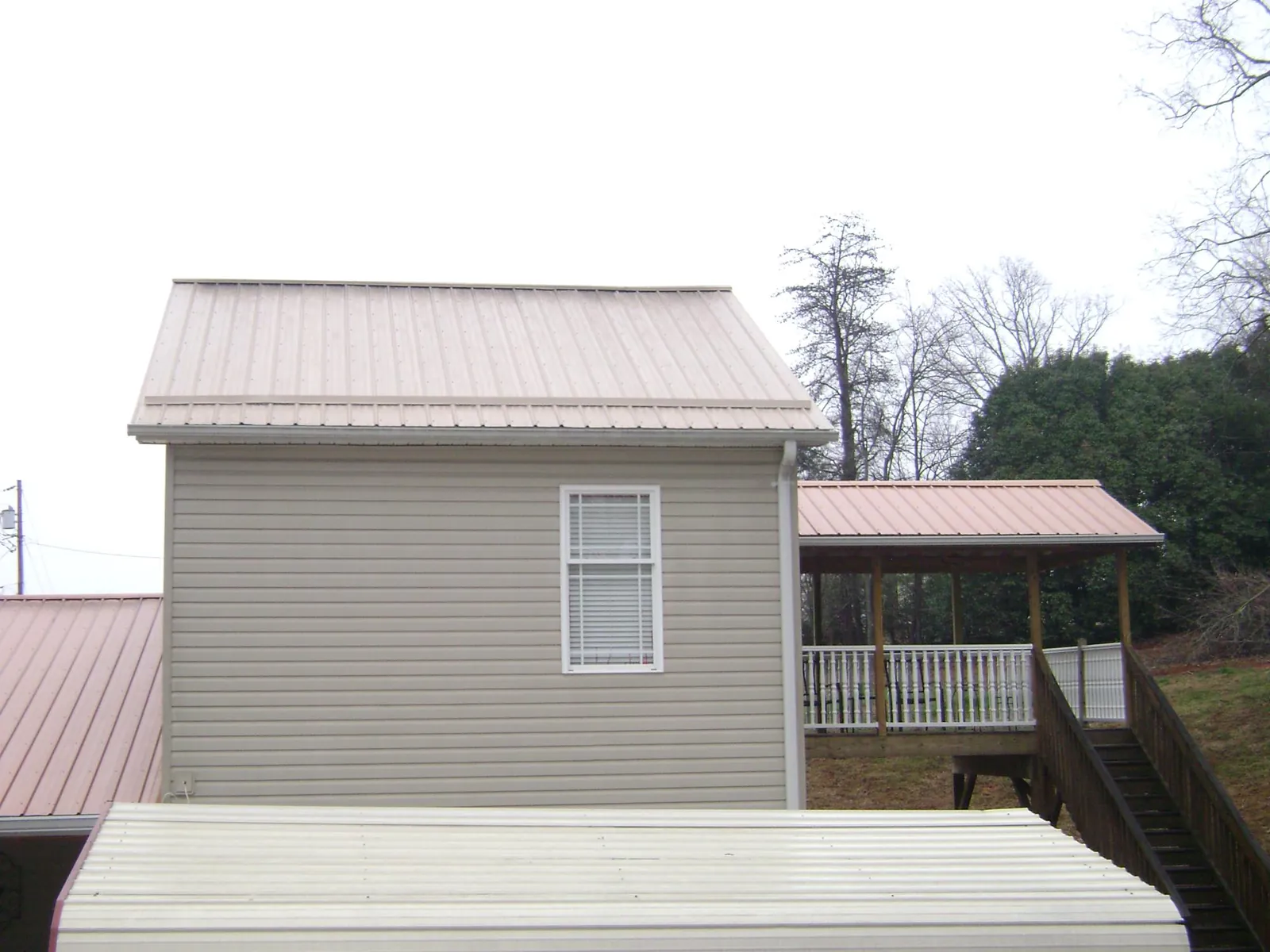 Tan metal roofs on a two story addition and attached porch, from a Roof Replacement job in Mountain City