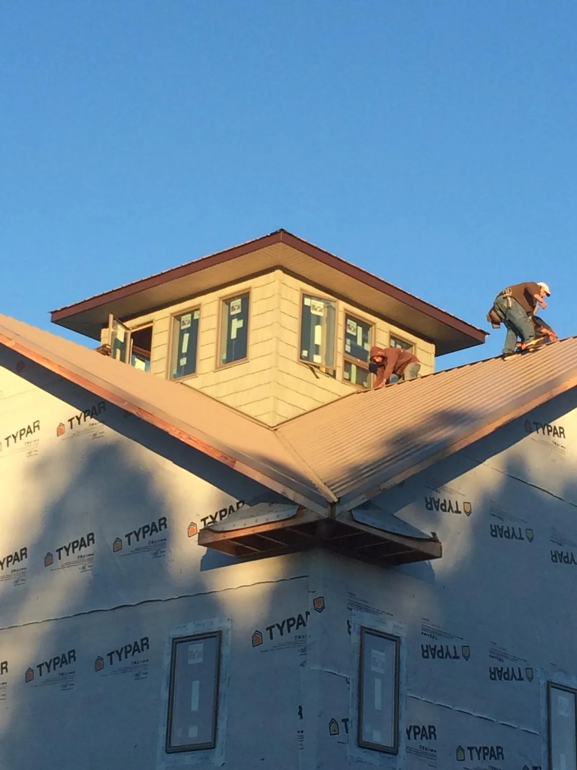 Roofers working around a rooftop cupola on a new metal roof at sunset — Roof Waterproofing in Mountain City by Roofing Brothers